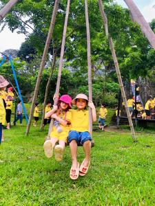 two children sitting on a swing at a park at Nature Key Retreat Gia Trịnh - Ba Vì in Hanoi