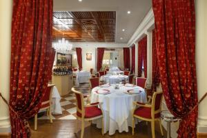 ein Esszimmer mit Tischen, Stühlen und roten Vorhängen in der Unterkunft Savoy Beach Hotel & Thermal Spa in Bibione