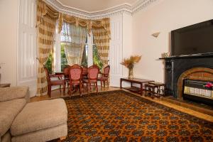 - un salon avec une cheminée, une table et des chaises dans l'établissement Pass the Keys Traditional 5 Bed Bellahouston Glasgow Sleeps 10, à Glasgow