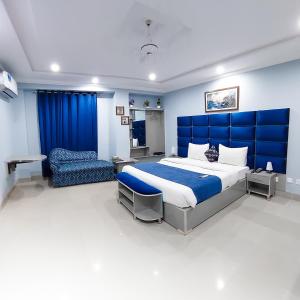 ein Schlafzimmer mit einem großen Bett und einem Stuhl in der Unterkunft Hotel Crown Inn in Multan