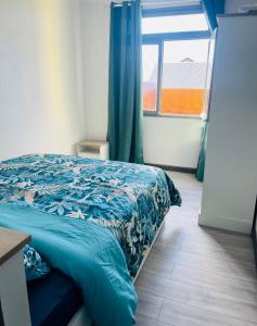 - une chambre avec un lit doté d'une couette bleue et d'une fenêtre dans l'établissement Villa des pruniers, à Saint-Denis