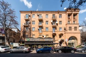 duży ceglany budynek z samochodami zaparkowanymi przed nim w obiekcie hotelise I Palermo Apartment w Erywaniu