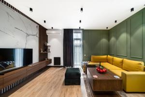 a living room with a yellow couch and a flat screen tv at hotelise I Palermo Apartment in Yerevan