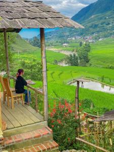 una mujer sentada en un porche con vistas a un valle en SaPa Farmer House en Sa Pa