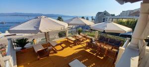 a deck with tables and chairs and umbrellas at Dalmatian Villa Denis in Bol