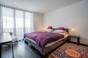 a bedroom with a large bed with purple sheets and a rug at Mountain View Apartment in Zermatt - Denali in Zermatt