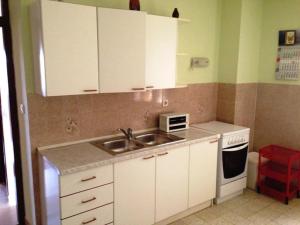 a kitchen with white cabinets and a sink and a stove at Apartman Pavin, Poljana in Poljana