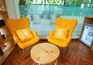 two yellow chairs and a table in front of a window at Bloom Hotel Koregaon Park in Pune