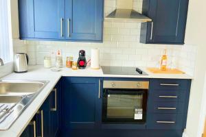 una cocina con armarios azules y fregadero en Royal Haven, en Hillsborough