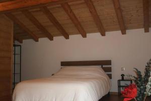 a bedroom with a white bed with wooden ceilings at Chalet au cœur des bois in Larringes