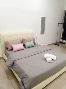 ein Bett mit rosa und grünen Kissen darauf in der Unterkunft JOVIAL COZY&STYLISH 2STORYHOUSE 4ROOM@BMJURU in Bukit Mertajam