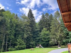 a park with a bench and a picnic table in the grass at Chalet au cœur des bois in Larringes