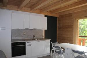a kitchen with white cabinets and a table and a table and chairs at Chalet au cœur des bois in Larringes