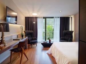 a hotel room with a bed and two chairs and a desk at Andorra Park Hotel in Andorra la Vella