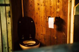 a wooden bathroom with a toilet and a roll of toilet paper at Heydon Grove Farm by Feather Down in Heydon