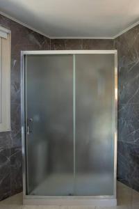 uma porta de duche em vidro num quarto com paredes em mármore em Captivating Lake & Oceanview Getaway House em Meneou