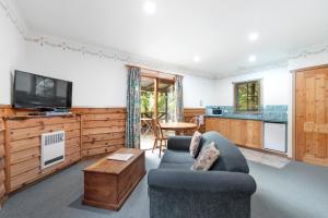 a living room with a couch and a tv at Cradle forest inn in Moina