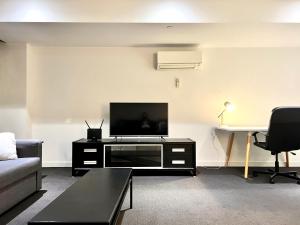 uma sala de estar com uma televisão, um sofá e uma mesa em ReadySet Apartments on Little Collins em Melbourne