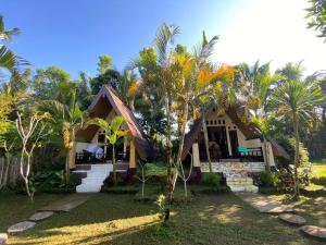 a house with palm trees in front of it at MATRAHAYA BUNGALOWS in Tetebatu