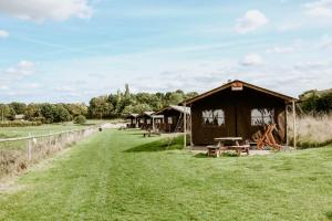 a group of huts in a field with grass at Heydon Grove Farm by Feather Down in Heydon