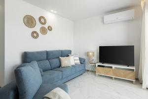 uma sala de estar com um sofá azul e uma televisão em Miral 5 Sea front by HD Properties em Quarteira