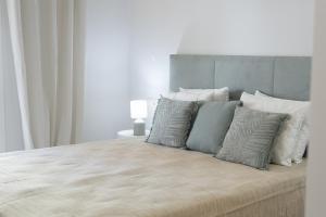 um quarto com uma cama grande e almofadas brancas e cinzentas em Miral 5 Sea front by HD Properties em Quarteira