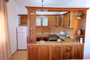 een keuken met houten kasten en een witte koelkast bij Vila Suljo in Ksamil