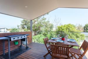 uma mesa e cadeiras num deque com comodidades para churrascos em Silversands Beach Cottage em Mount Martha