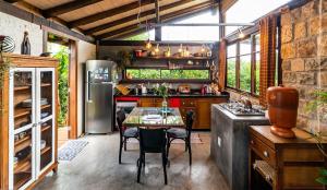 a kitchen with a table and a refrigerator at Casinha Jardim in Imbituba