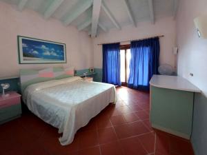 a bedroom with a large bed and blue curtains at Villa La Rocca in Stintino
