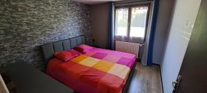 a colorful bed in a room with a brick wall at Appartement "Les Calins" in Ney