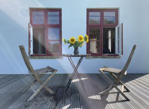 two chairs and a table with a vase of flowers and windows at Projektraum Obst und Sterne 