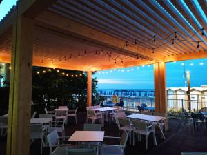 a patio with tables and chairs and a view of the ocean at Hotel Cola Frontemare in Bellaria-Igea Marina