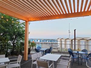 a patio with tables and chairs on a deck at Hotel Cola Frontemare in Bellaria-Igea Marina