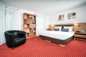 a bedroom with a large bed and a black chair at Apart Business Hotel in Stuttgart