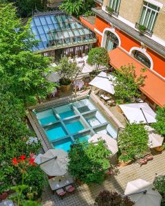 パリにあるホテル ラッフルズ ロイヤル モンソー パリのテーブルとパラソル付きのスイミングプールのオーバーヘッドビュー