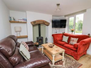 a living room with a leather couch and a table at Min Y Nant in Welshpool
