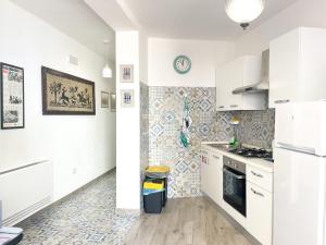 a kitchen with white cabinets and a tile wall at Affittacamere DOMO AGORA' in Tertenìa
