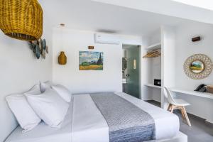 a white bedroom with a bed and a chair at Skopelos Holidays Hotel & Spa in Skopelos Town