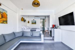 a living room with a couch and a tv at Skopelos Holidays Hotel & Spa in Skopelos Town