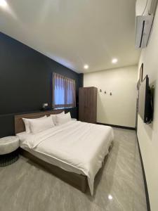 - une chambre avec un grand lit blanc et une télévision dans l'établissement 亞士密民宿, à Puli
