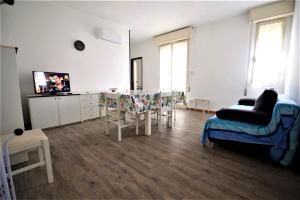 sala de estar con mesa, sillas y TV en LAURA confortevole e rilassante appartamento climatizzato a due passi dalla spiaggia en Lido di Scacchi
