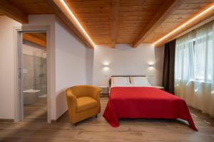 AgriRelais San Giovanni في Capestrano: غرفة نوم بسرير احمر وكرسي اصفر
