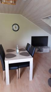 a dining room table with chairs and a clock on the wall at Stadt-Land-Fluss in Wickede (Ruhr)