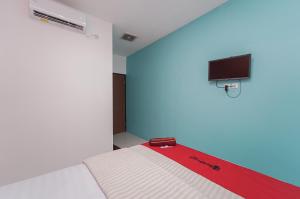 um quarto com uma cama e uma televisão na parede em RedDoorz Syariah at MN One Cempaka Putih em Jakarta