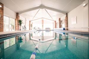 a swimming pool with a person paddling in it at The Threshing Barn - relaxing countryside spa break in Pentney