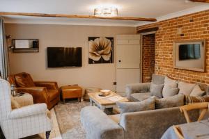 uma sala de estar com sofás e uma televisão em The Threshing Barn - relaxing countryside spa break em Pentney