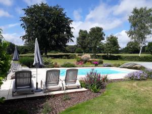 una piscina con sillas y sombrillas en un patio en Gite de la Houssière en Joué-du-Bois