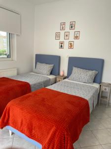 1 dormitorio con 2 camas con sábanas rojas y grises en Pearl of Paralia Akrata en Akrata