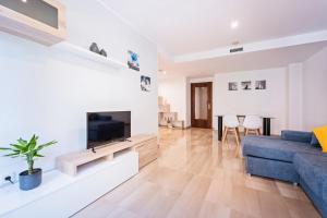 sala de estar con sofá azul y TV en Aparthotel Napols - Abapart en Barcelona